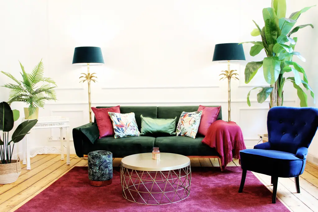 Wohnzimmer des Tropical ARTstudio: grünes Samtsofa, blauer Sessel, Palmen und Dschungeltapete